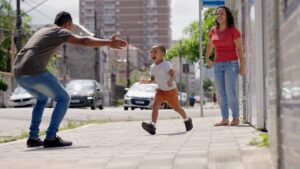Father reuniting with young child during Florida timesharing exchange as mother looks on