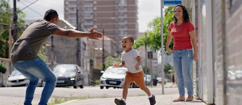 Father reuniting with young child during Florida timesharing exchange as mother looks on
